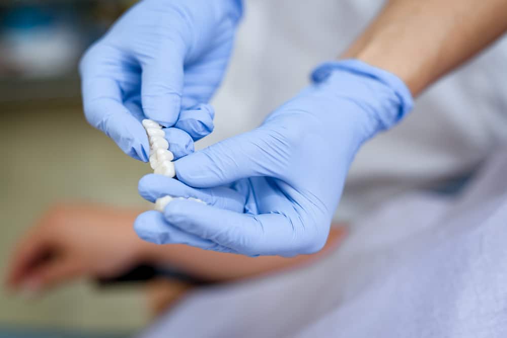 Dentist showing porcelain crowns to the patient. Close-up. Focus on ceramics implant.